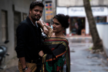 A brunette Indian Bengali romantic couple in traditional wear interacting between themselves in the...