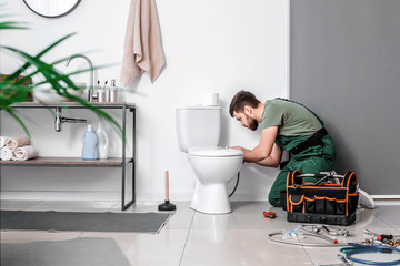 Plumber installing toilet bowl in bathroom