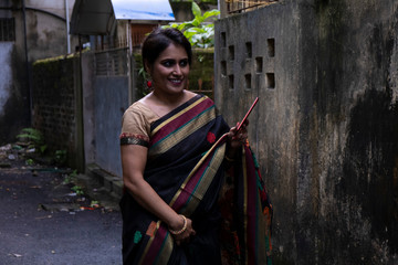 Portrait of a beautiful brunette Indian bengali thoughtful woman in traditional wear sari standing...