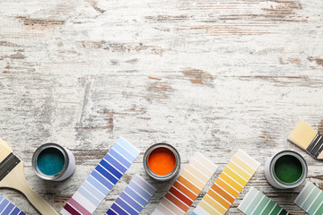 Color swatches with paints and brushes on wooden table