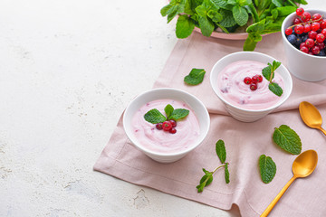 Obraz na płótnie Canvas Bowls with tasty yogurt and berries on white background