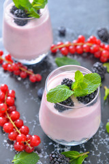 Glass with tasty yogurt and berries on table