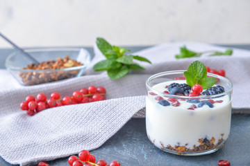 Glass with tasty yogurt, granola and berries on table