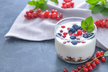 Glass with tasty yogurt, granola and berries on dark background