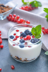 Glass with tasty yogurt, granola and berries on dark background