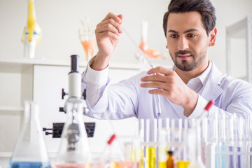 Attractive happiness scientist man lab technician assistant analyzing sample in test tube at laboratory. Medical, pharmaceutical and scientific research and development concept.