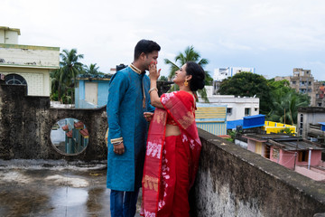 A brunette Indian Bengali romantic couple in traditional wear enjoying themselves standing on the...