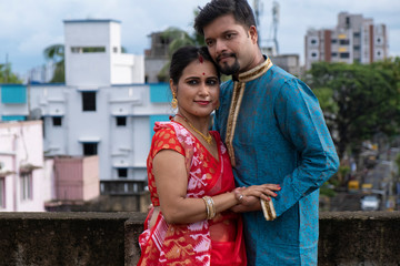 A brunette Indian Bengali romantic couple in traditional wear enjoying themselves standing on the...