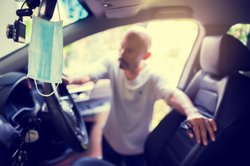 Hygienic masks hanging on rear view mirror with blurry driver. Daily preparation for the prevention...