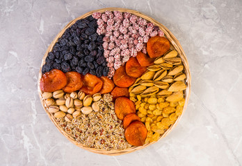 Wooden plate with a set of nuts, apricots, raisins, sesame