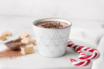 Cup of hot chocolate and candy canes on light table