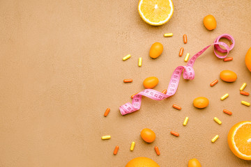 Measuring tape, fruits and weight loss pills on color background