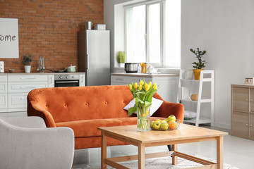 Interior of modern studio apartment with bouquet of spring flowers on table