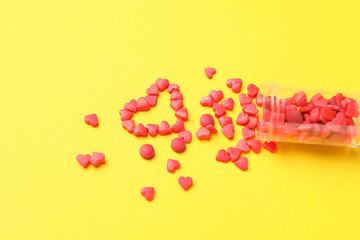 Jar and heart made of pills on color background