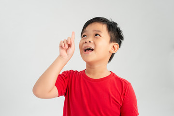 Cheerful little boy pointing up over white background