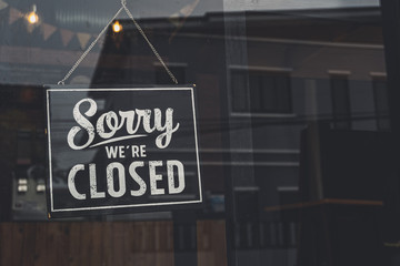 Vintage sorry we are closed sign hanging on a glass door.