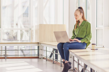 Young beautiful woman sits with a laptop and a cup of coffee