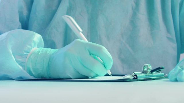 Influenza pandemic. Sick list. Doctor in protective gloves writing medical report.