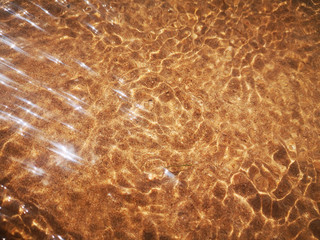 Golden sand can be seen behind the water ripples with beautiful sunny highlights