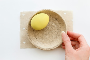 A woman holds ceramic bowl with one Easter egg.