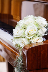 Wedding bouquet of white roses lying on the piano keys.