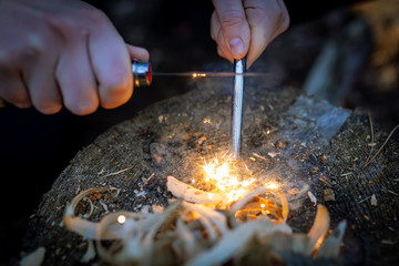 Outdoors makeing fire by flint. Closeup view.