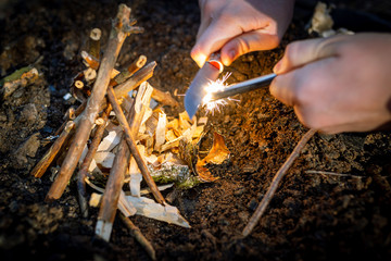 Outdoors makeing fire by flint. Closeup view.