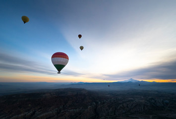 View of a volcano Mount Kayseri of balloons seen from Goreme, Cappadocia with beautiful sunrise and colourful, golden, orange, pink and blue sky. It's fun, excited and impress activity at Turkey.