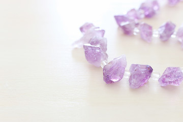 Purple gemstones beads on white wooden background