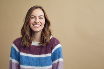 Portrait of a young woman wearing a multicolored sweater on a modern background 