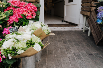 A small business for selling flowers. Blue and pink hydrangeas, white flowers in a street store. Entrense to the flower shop.