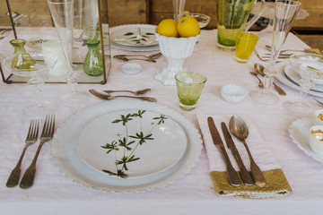 Beautiful table setting on wooden baBeautiful table setting on white table cloth with green and yellow decor.ckground