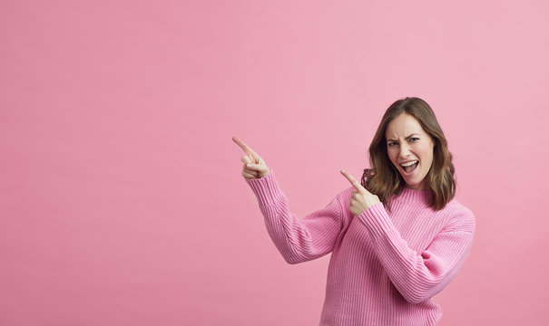 young woman in pink dress pointing at the pink copy space 