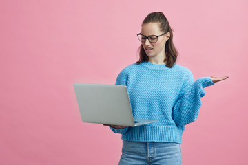 Portrait of student having computer problems while standing on a nice colorful pink background 