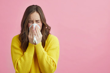 Pretty girl is Sneezing into a tissue because of her allergy or cold  - obrazy, fototapety, plakaty