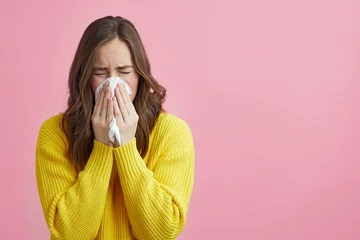Poster Pretty girl is Sneezing into a tissue because of her allergy or cold  © Martin Villadsen