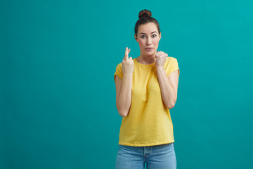 Young woman is crossing her finger and hoping that its going her way