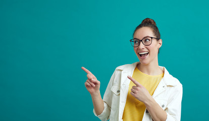 Happy young woman pointing at colorful copyspace