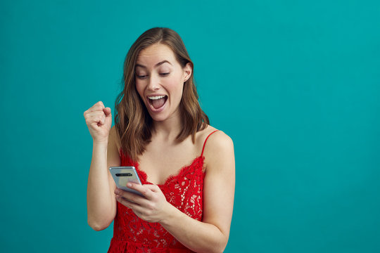 Portrait Of Attractive Woman Getting Good News On Her Phone While Wearing A Date Night Dress