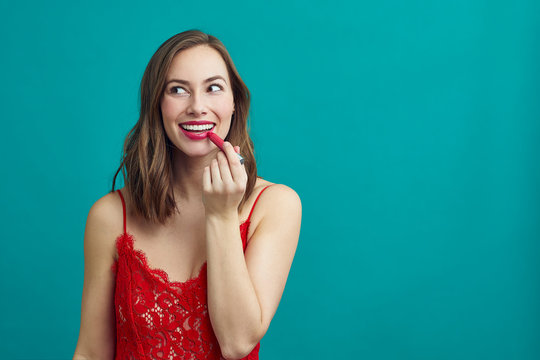 Pretty Girl Putting On Lipstick While Wearing A Beautiful Red Dress, Getting Ready For Her Date