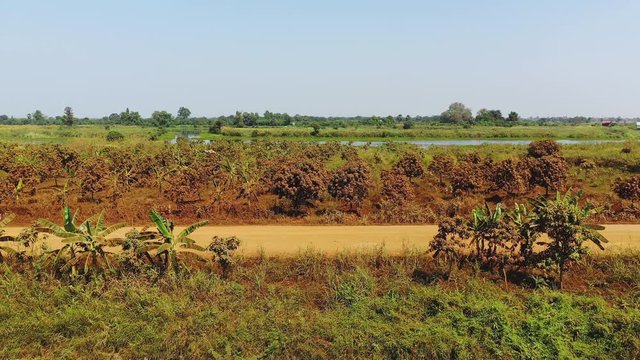 Un camion circule sur une route de terre et de sable orange avec la campagne en arri&egrave;re plan en faisant beaucoup de poussi&egrave;re vers Phnom Penh, au Cambodge, en Asie.