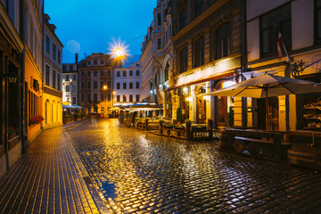 Riga, Latvia. Traditional Cafe In Lighting At Evening Or Night Illumination In Old Town In Tirgonu Street