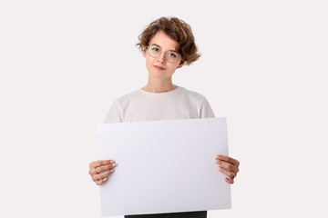 Pretty young woman with eyeglass holding empty blank paper board with copy space for text.