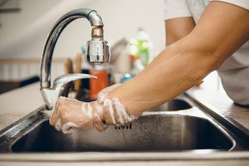 Mature man and woman washing hands in the kitchen