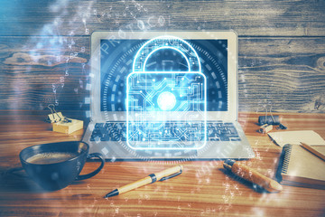 Double exposure of desktop with computer and lock icon hologram. Concept of data safety.