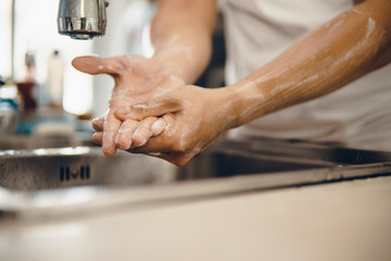 Cropped shot of an unrecognizable man washing his hands at home to prevent spreading of the coronavirus ( Covid-19)
