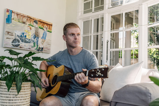 Man playing guitar at home during COVID-19 Lockdown - Powered by Adobe