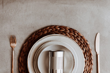 Can of food in a plate on rattan dining mat with golden cutlery on a table flat lay