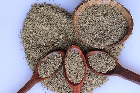 Ajwain seeds in a wooden spoon over white background