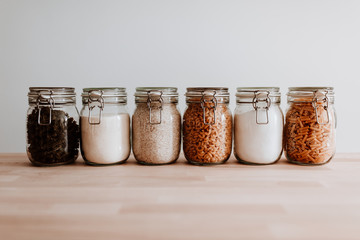 Six glass jars full with dried uncooked food ingredients - obrazy, fototapety, plakaty